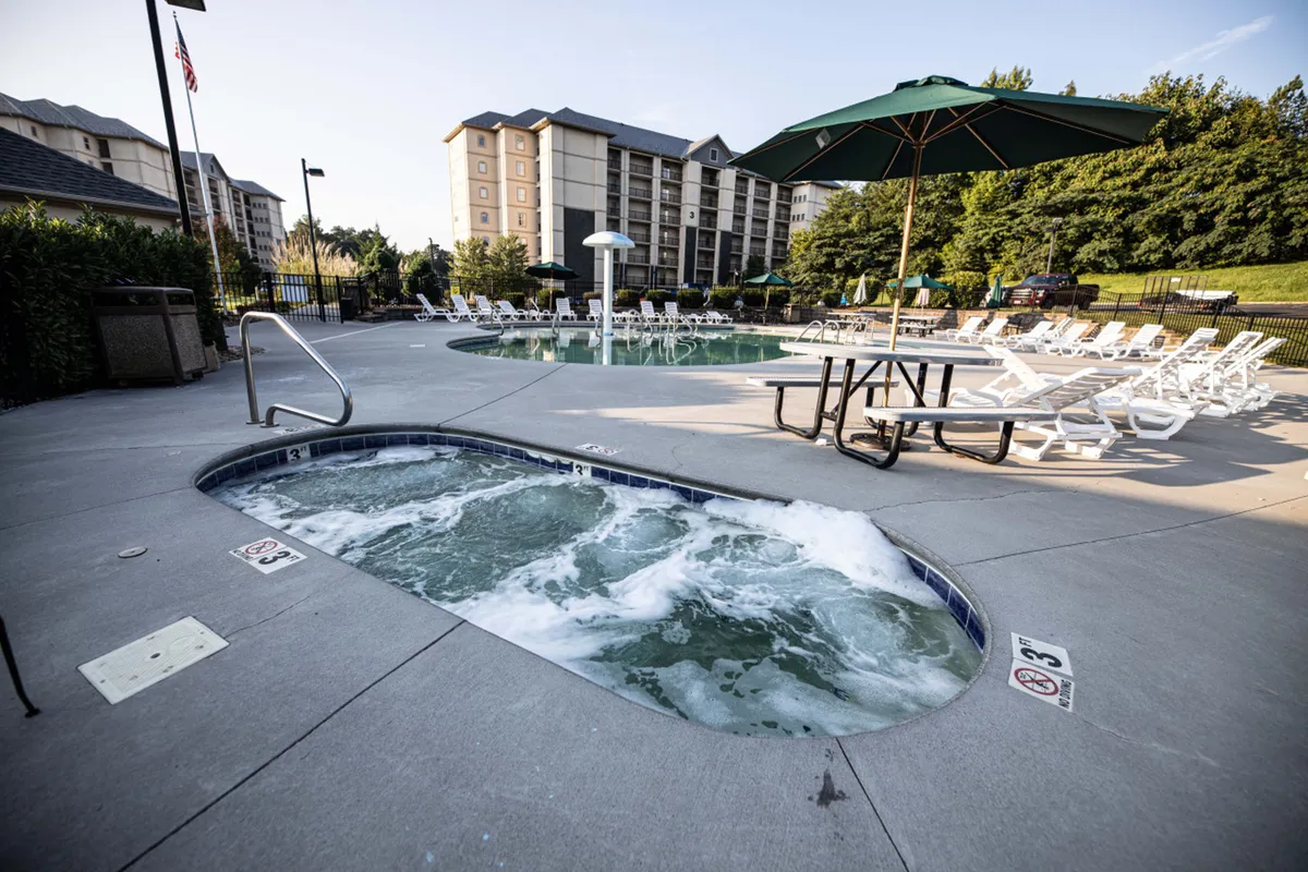 An inviting exterior pool area features a heated swimming pool, a hot tub, lounge chairs, and a picnic table, all set against a tranquil backdrop. The pool is accessible year-round and the space encourages both quiet relaxation and group socializing.