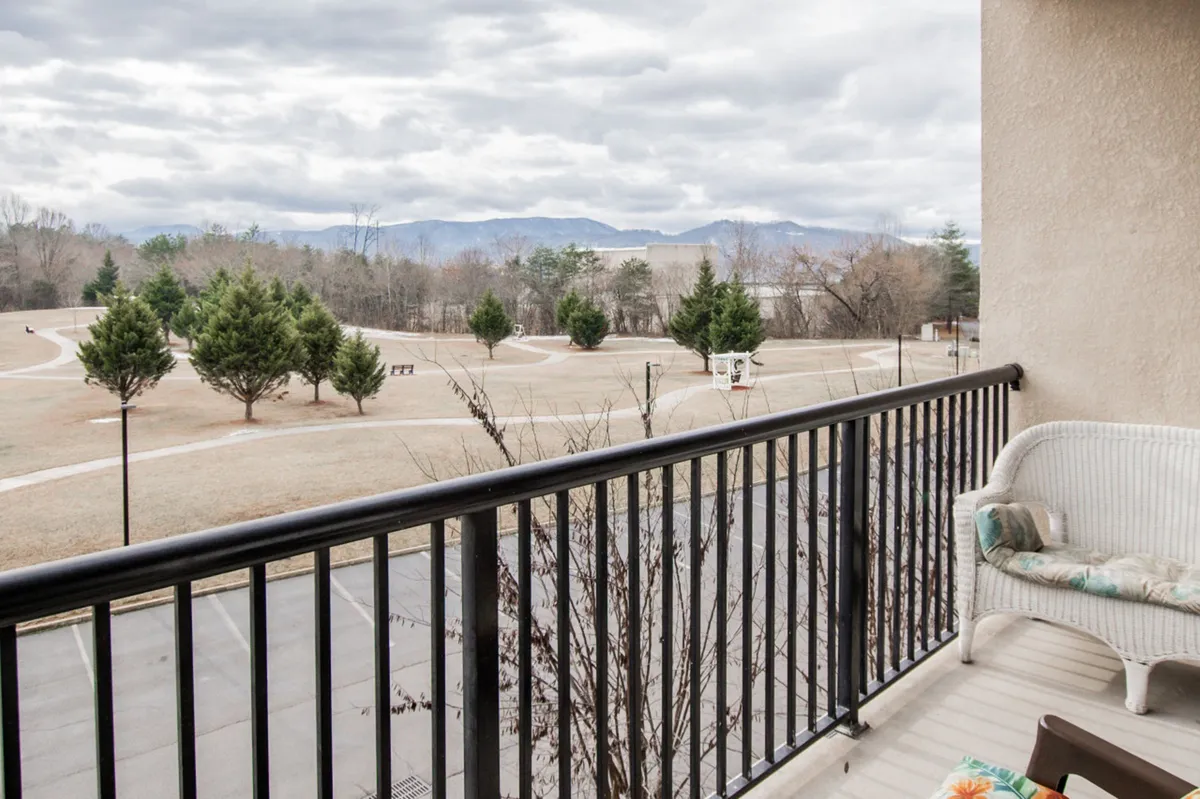 A third-floor balcony with comfortable outdoor seating overlooks a picturesque mountain landscape dotted with trees. The space feels private yet connected to the resort's natural surroundings, inviting guests to relax, socialize, and take in the views.