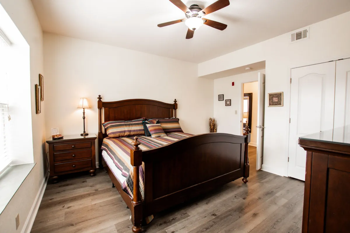 The image shows a beautifully styled bedroom with a plush bed, warm nightstand, and soft lamp lighting, creating an inviting and peaceful atmosphere perfect for relaxing after a day of exploring Pigeon Forge.