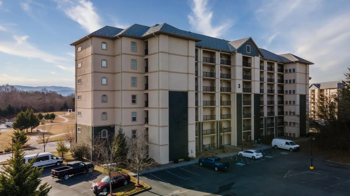 The exterior of the building with a view of the parking lot and surrounding greenery, showing the building's entrance and ample, convenient parking.