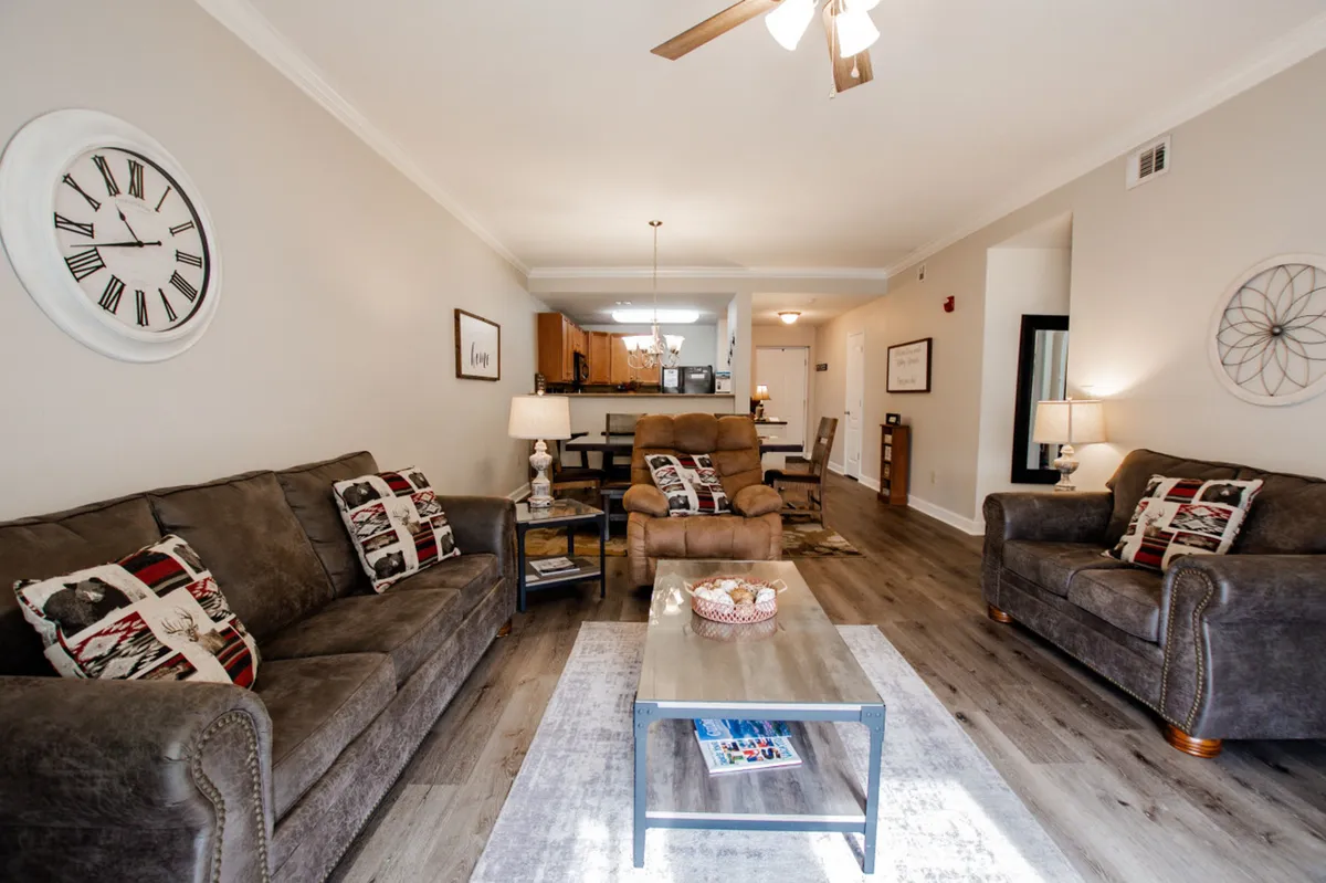 A cozy living room setup features plush sofas arranged around a coffee table, with a wall clock and inviting decor. The atmosphere is perfect for game nights, casual gatherings, or relaxing after a day of adventure.