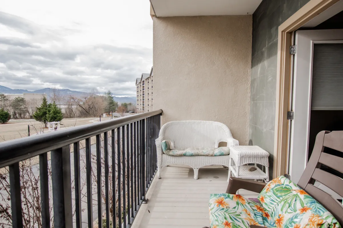 This image captures an exterior balcony scene with comfortable wicker chairs, a sturdy railing, and sweeping views of the mountain landscape. The tranquil setting suggests the perfect spot for morning coffee or unwinding after a day of adventure, inviting guests to connect with the outdoors.