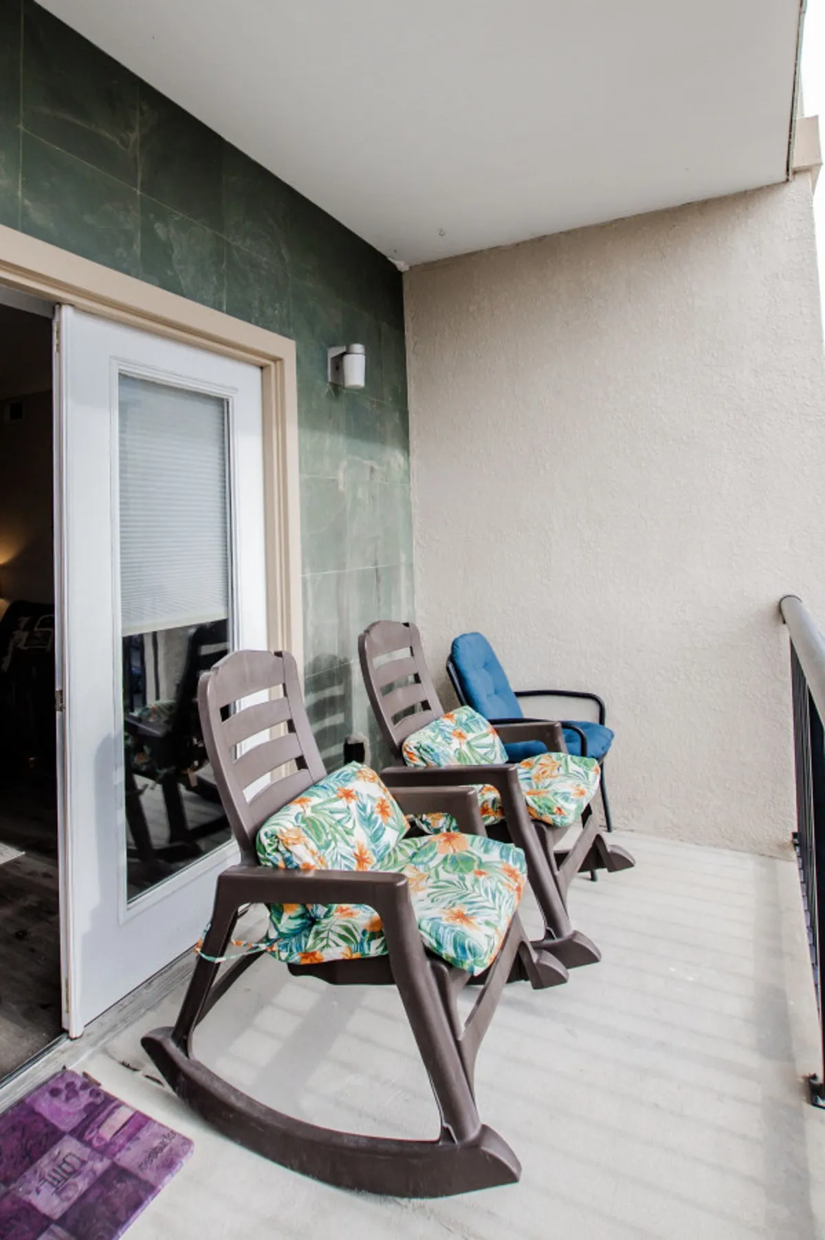 This exterior image features a cozy front porch with rocking chairs and colorful cushions, suggesting a welcoming retreat just steps away from the surrounding excitement. The doorway hints at easy transitions from the condo to the vibrant neighborhood beyond.